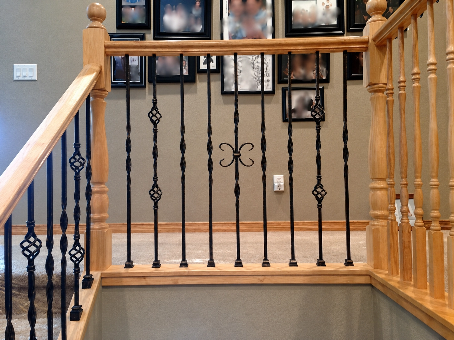 Twist and basket iron balusters installed below stained wood handrail